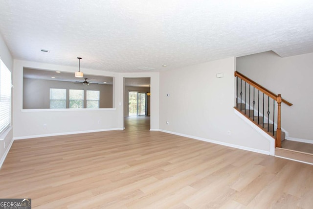 1924 Sweet Flag Rd, Lawrenceville, GA 30045 - unfurnished living room with light wood-style floors, a textured ceiling, a ceiling fan, stairway, and baseboards