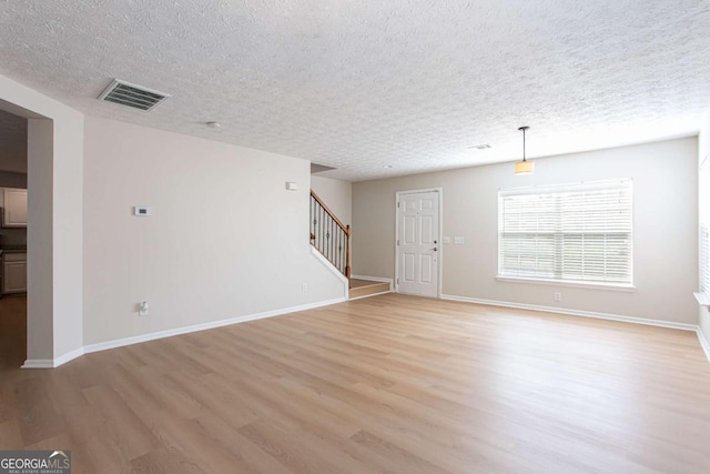 1924 Sweet Flag Rd, Lawrenceville, GA 30045 - unfurnished living room featuring light wood-style floors, stairs, a textured ceiling, and baseboards