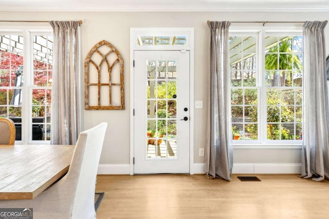entryway with baseboards, visible vents, crown molding, and wood finished floors
