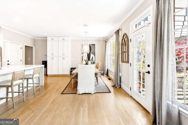 dining space featuring baseboards, light wood-style floors, and ornamental molding
