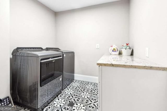 clothes washing area featuring separate washer and dryer, light tile patterned flooring, baseboards, and laundry area