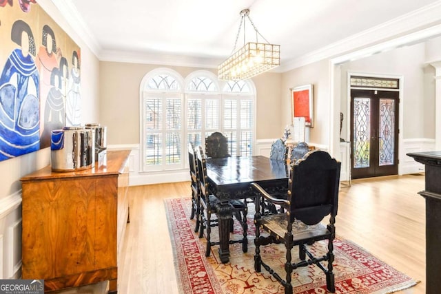 dining room featuring french doors, a wainscoted wall, ornamental molding, and light wood-style floors