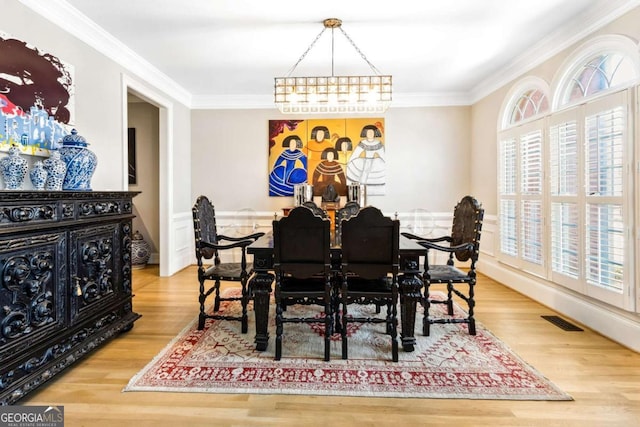 dining area featuring visible vents, crown molding, and wood finished floors