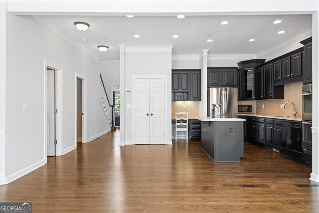 kitchen featuring light countertops, a breakfast bar area, a kitchen island, a sink, and appliances with stainless steel finishes