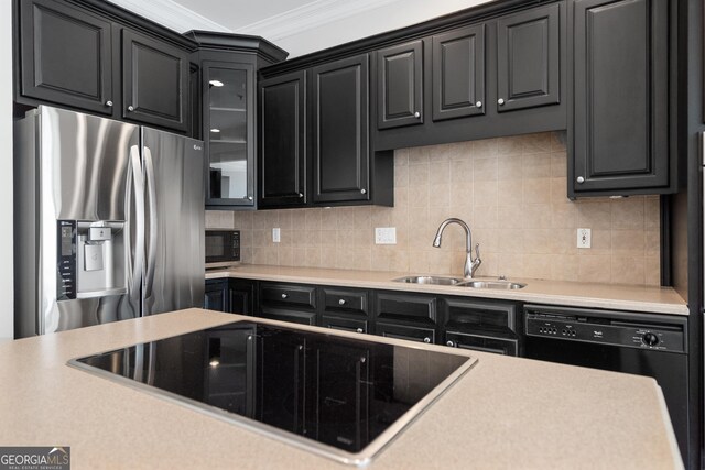 kitchen with light countertops, tasteful backsplash, crown molding, a sink, and black appliances