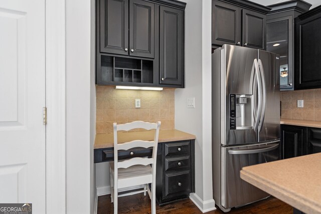 kitchen featuring light countertops, dark wood-style flooring, stainless steel fridge with ice dispenser, backsplash, and dark cabinets