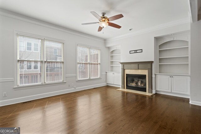 unfurnished living room featuring dark wood finished floors, crown molding, baseboards, and built in shelves