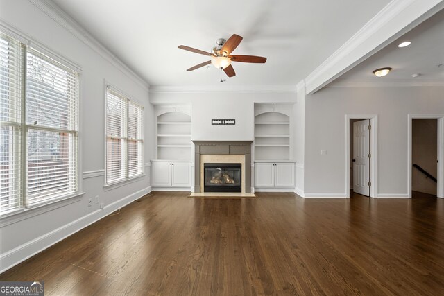 unfurnished living room featuring crown molding, dark wood-type flooring, baseboards, ceiling fan, and built in features