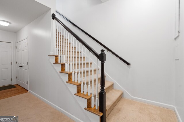 stairway featuring baseboards and carpet