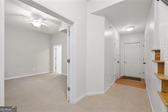 hall featuring light colored carpet and baseboards