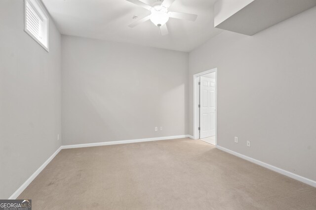 unfurnished room with light carpet, baseboards, and a ceiling fan