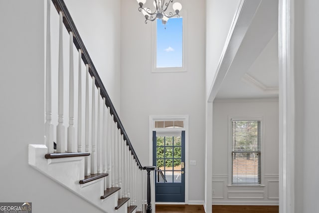 entrance foyer with a wainscoted wall, an inviting chandelier, stairway, and plenty of natural light