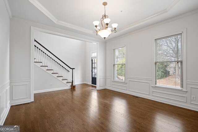 foyer entrance featuring crown molding, stairway, a chandelier, wood finished floors, and a decorative wall