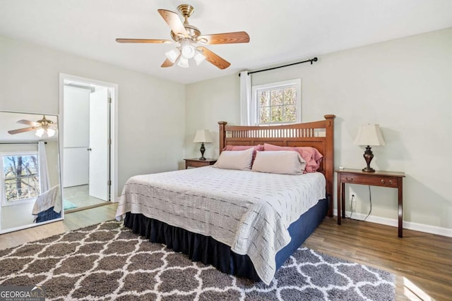 bedroom featuring baseboards, wood finished floors, and multiple windows