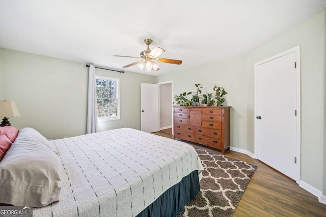 bedroom with a ceiling fan, baseboards, and wood finished floors