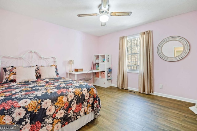 bedroom with baseboards, visible vents, wood finished floors, and a ceiling fan