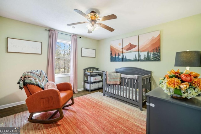 bedroom with baseboards, wood finished floors, and a nursery area