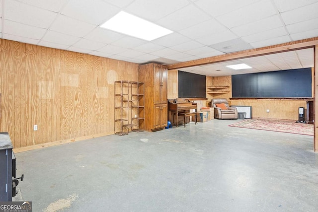 basement with a paneled ceiling and wooden walls