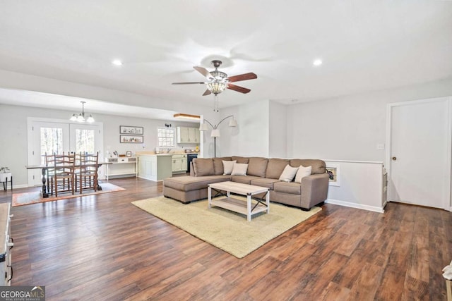 living room with dark wood-style floors, recessed lighting, and ceiling fan with notable chandelier