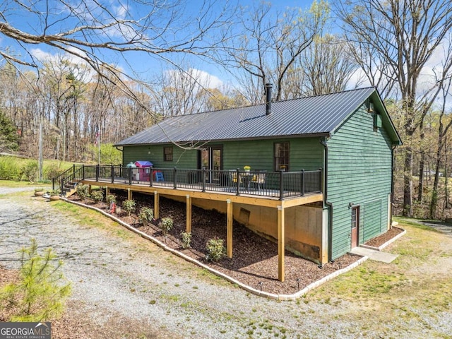 back of house with metal roof and a wooden deck