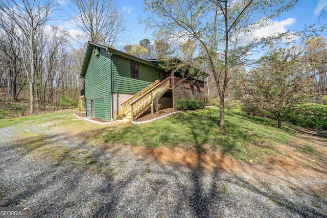 exterior space with a wooden deck, stairs, and a front lawn