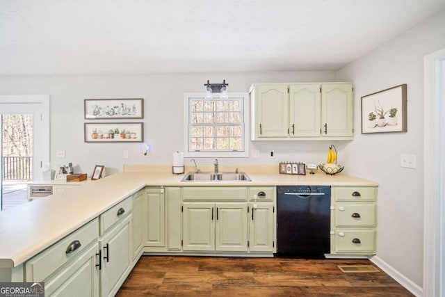 kitchen featuring light countertops, dark wood-type flooring, a sink, black dishwasher, and a peninsula