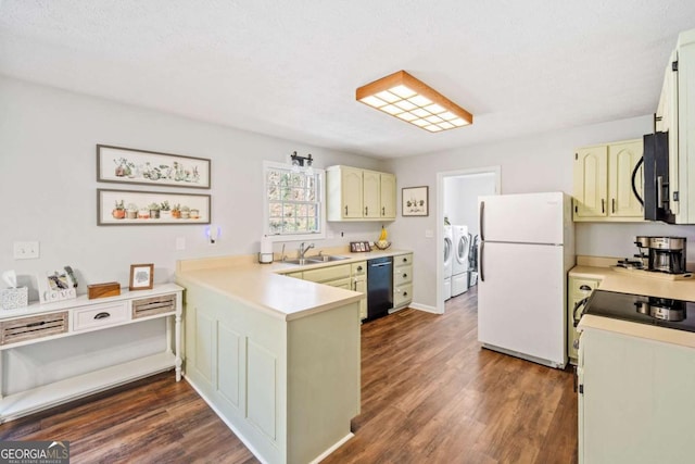kitchen with a peninsula, dark wood-type flooring, a sink, black appliances, and separate washer and dryer