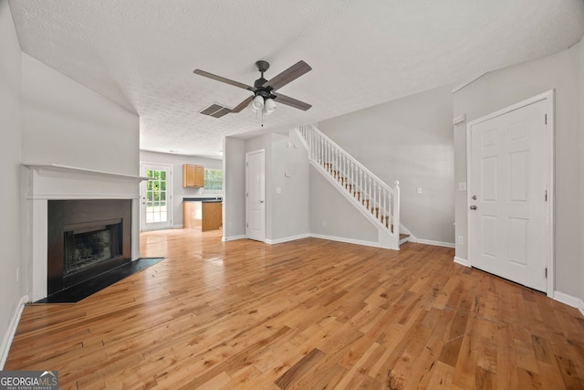 60 Charlotte Blvd, Stockbridge, GA 30281 - unfurnished living room with light wood-type flooring, a textured ceiling, stairs, and ceiling fan