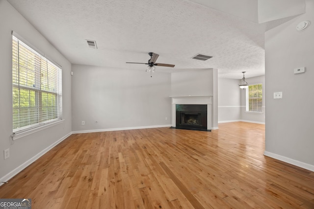 60 Charlotte Blvd, Stockbridge, GA 30281 - unfurnished living room featuring a fireplace with flush hearth, visible vents, baseboards, light wood-style flooring, and ceiling fan