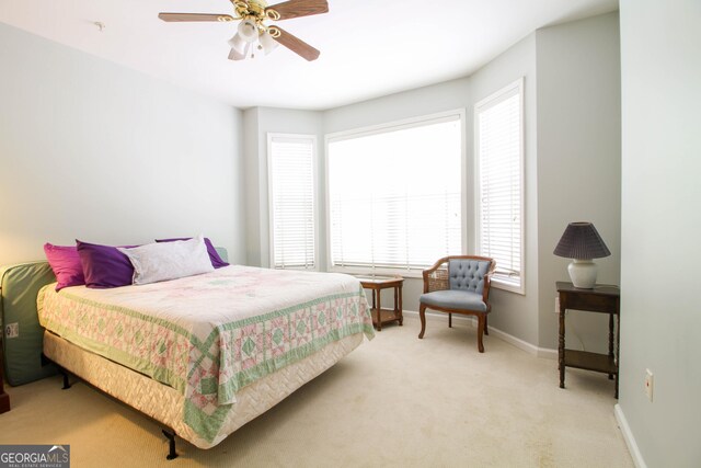 bedroom featuring light colored carpet, baseboards, and a ceiling fan