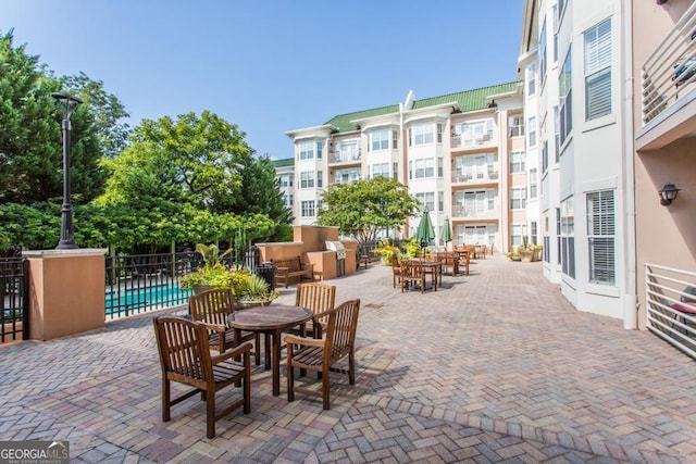 view of patio with outdoor dining area, fence, and a community pool