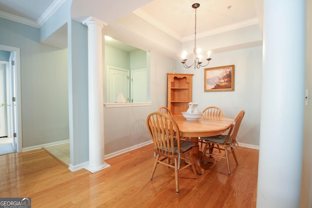 dining room with a chandelier, baseboards, light wood-style floors, ornamental molding, and ornate columns