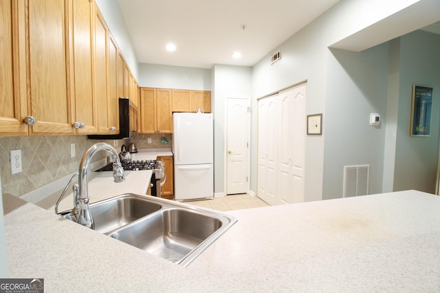 kitchen with visible vents, tasteful backsplash, a sink, and freestanding refrigerator