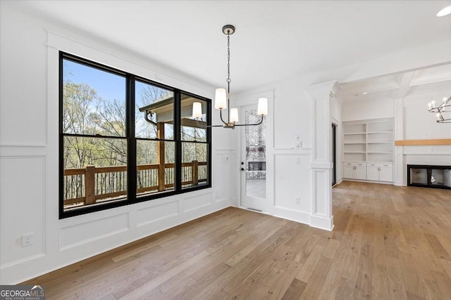 100 Forest Pl, Forsyth, GA 31029 - unfurnished dining area with a chandelier, a decorative wall, light wood finished floors, built in features, and a glass covered fireplace