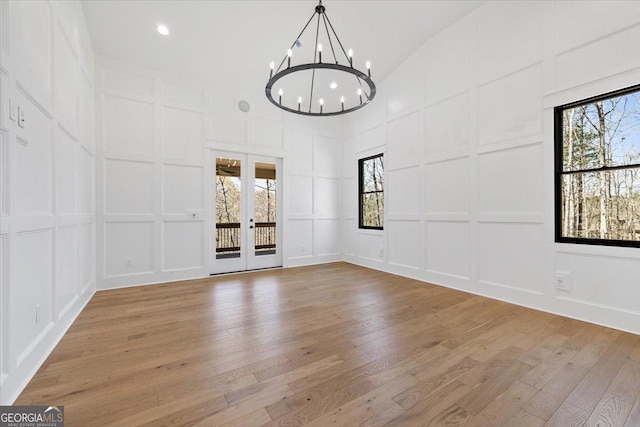 100 Forest Pl, Forsyth, GA 31029 - spare room featuring a decorative wall, high vaulted ceiling, a chandelier, light wood-style flooring, and french doors