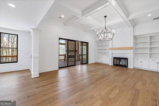 100 Forest Pl, Forsyth, GA 31029 - unfurnished living room featuring light wood-style flooring, healthy amount of natural light, beam ceiling, a fireplace, and a chandelier
