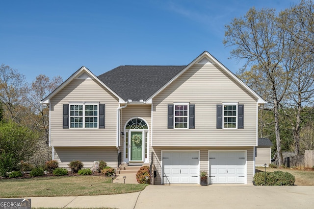 split foyer home featuring a garage, a front lawn, concrete driveway, and roof with shingles
