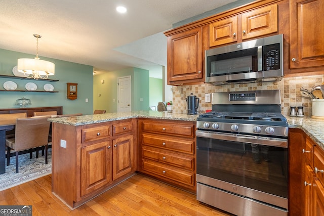 kitchen with brown cabinets, stainless steel appliances, light wood-style floors, and a peninsula