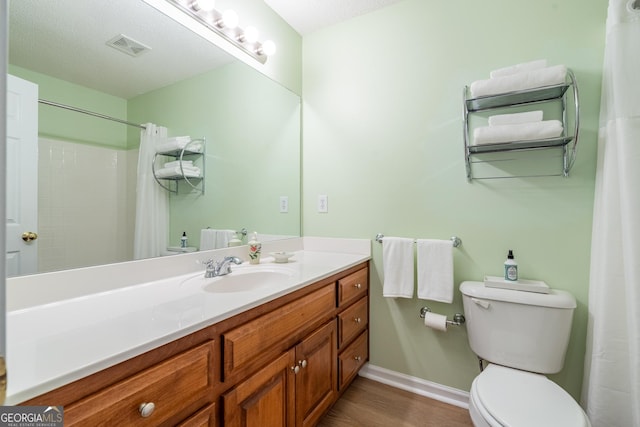 full bathroom with vanity, toilet, baseboards, visible vents, and wood finished floors