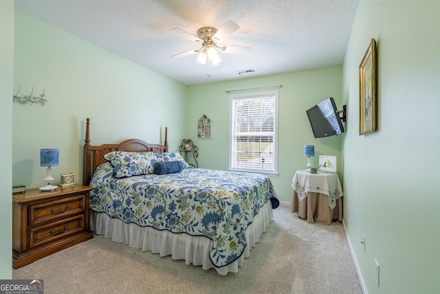 carpeted bedroom featuring baseboards, visible vents, ceiling fan, and a textured ceiling
