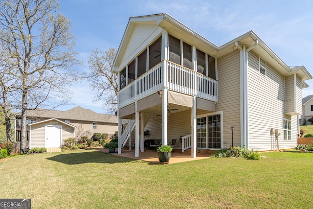 back of house with an outdoor structure, a sunroom, a patio area, ceiling fan, and a lawn