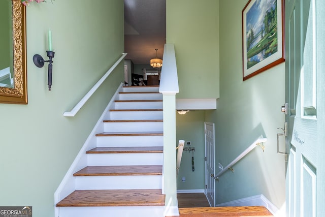 stairs with baseboards and an inviting chandelier