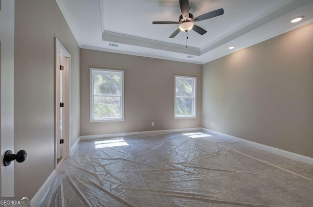 unfurnished room featuring ornamental molding, baseboards, visible vents, a ceiling fan, and a tray ceiling