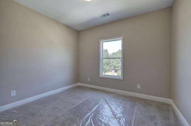 carpeted empty room featuring baseboards and visible vents