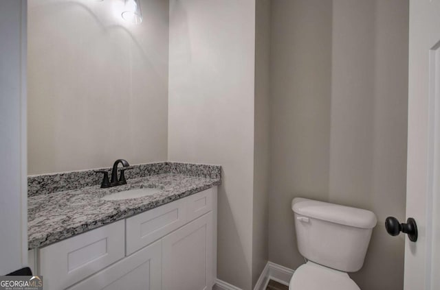 bathroom featuring toilet, vanity, and baseboards
