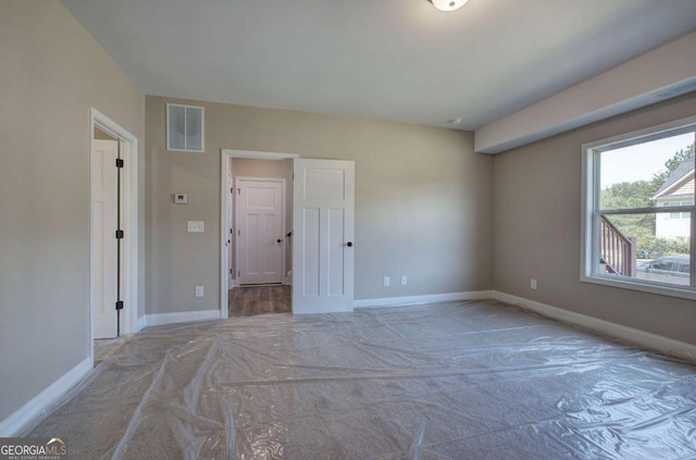 carpeted spare room featuring visible vents and baseboards