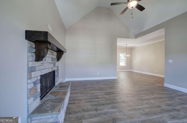 unfurnished living room featuring a stone fireplace, vaulted ceiling, baseboards, wood finished floors, and ceiling fan with notable chandelier