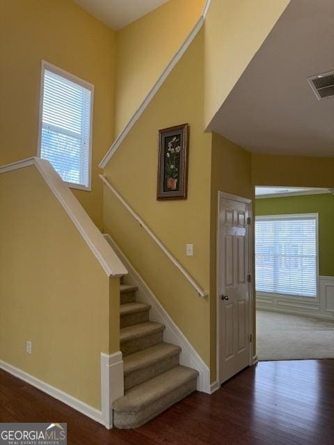 staircase featuring visible vents, a wealth of natural light, and wood finished floors