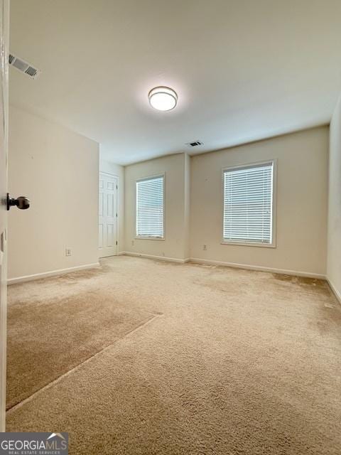spare room with baseboards, visible vents, and light colored carpet