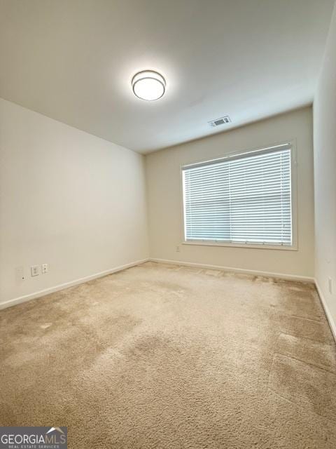 empty room featuring baseboards, visible vents, and light colored carpet